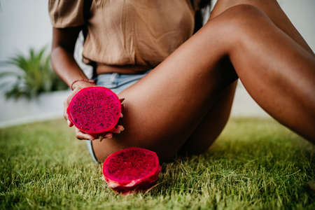tanned girl in a bikini holding a slices of bright juicy tropical dragon fruit. soft focus.の写真素材