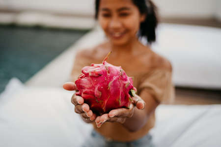 Asian girl holding whole tropical dragon fruit in her hands. beauty asian woman with pitaya - dragon fruitの写真素材