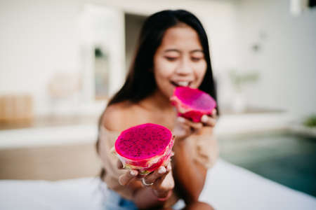 young asian girl in a holding a slices of bright juicy tropical dragon fruit. soft focusの写真素材