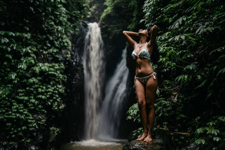 young asian girl in bikini In Front Of A Waterfallの写真素材