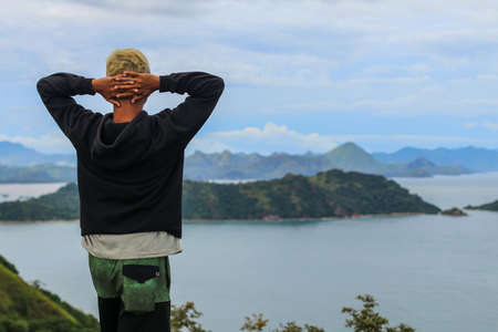 Portrait of young man on the top of hill wearing black jacket with the sea background in Labuan Bajo