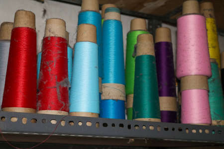 Set of colored threads for sewing on coils. Pile of big colorful spools of thread. Colored thread...