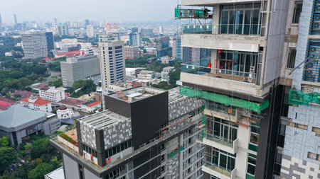 Java, Jakarta, Indonesia, May 20, 2022. Workers are using gondola as vertical trasport to install aluminum composite on the construction buildingのeditorial素材