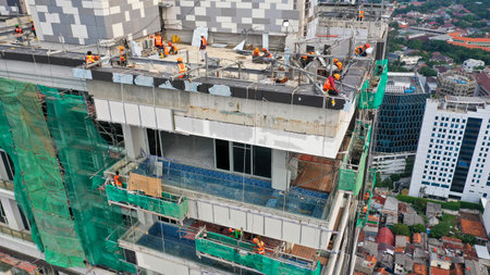 Java, Jakarta, Indonesia, May 20, 2022. Workers are using gondola as vertical trasport to install aluminum composite on the construction buildingのeditorial素材
