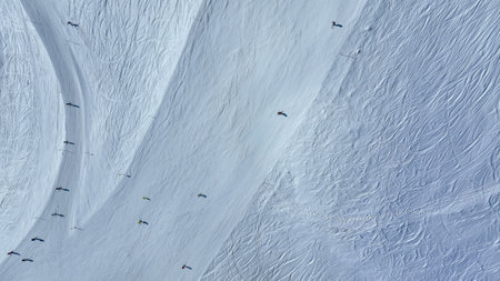 Skiers skiing downhill on a piste. Aerial View of Skier on Snowy Terrain. Top-down view of snowy...