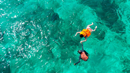Top down woman and man snorkeling crystal turquoise sea water coral reef. Aerial drone view, drone shot. Woman in bikini enjoy outdoor activity lifestyle, travel summer holiday vacationの写真素材