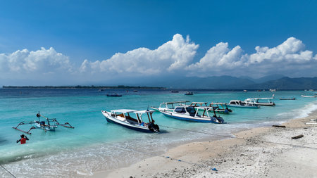 Coast of Gili Air Island, tourists enjoying clear water near the shore, many local boats. Drone fly over the coastlineの写真素材