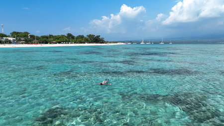 Woman lying on her back in the water. She has dark hair and is wearing a swimsuit. A woman floats relaxed on the surface of the water with her arms outstretched and her face is turned upの写真素材