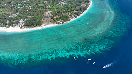 A aerial of a coral cay island surrounded by shallow reef and deep blue waterの写真素材