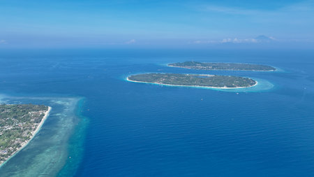 A breathtaking aerial view of the crystal clear water surrounding the tropical paradise of Gili Air, Gili Meno, and Gili Trawangan. Indonesian islands invite you to discover beaches and marine lifeの写真素材