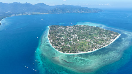 A breathtaking aerial view of Gili Air, Indonesia, surrounded by turquoise waters and vibrant coral reefs. The island lush greenery and white sandy beaches by from 500 meters upの写真素材