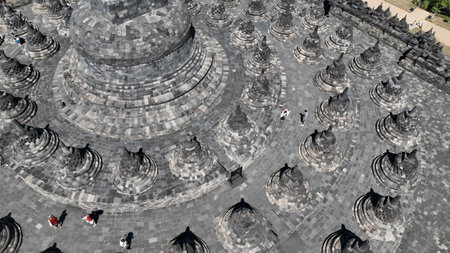 This aerial close up captures Borobudurs majestic central dome, surrounded by perfectly aligned stupas a stunning example of ancient Javanese architecture from aboveの写真素材