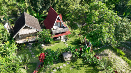 Charming traditional cottages nestled in lush tropical gardens, surrounded by vibrant greenery and colorful flowers a peaceful retreat in the heart of natureの写真素材
