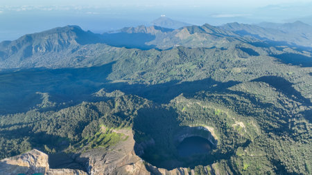 Kelimutu crater lakes glisten with surreal colors, set amongst shadows and forest ridges that hint at the volcanos dynamic spiritの写真素材