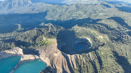 Turquoise and dark waters fill Kelimutu craters, bordered by steep volcanic cliffs and dense forests, painting an unforgettable Flores panoramaの写真素材