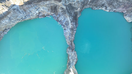 Artistic close up aerial shot of the boundary between the turquoise lakes of Kelimutu, highlighting the dramatic geology and intense water huesの写真素材