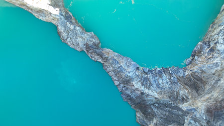 Close up of a rocky ridge divides two clear blue crater lakes, highlighting the surreal beauty of...