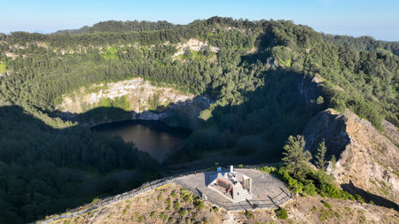 Close up aerial shot: tourists gather at Kelimutu summit platform for an unbeatable view of the crater and forest stretching into the distanceの写真素材