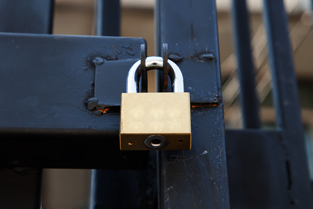 Closeup brass padlock on a black metal gate.の写真素材