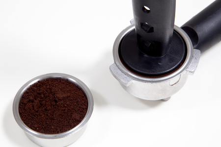 Portafilter filled with ground coffee on a white backgroundの写真素材