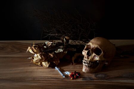 still life syringe and poison pill with the skull on wooden table.の写真素材