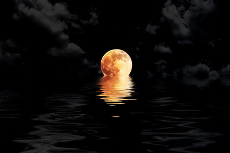 dark red full moon in cloud with water reflection closeup showing the details of the lunarの写真素材