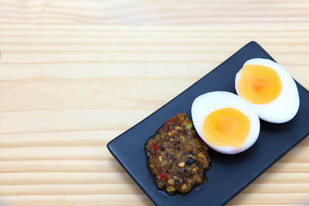 Thai food, chili paste with boiled egg on black rectangle plate, nam prik kai tom, on a wooden table.の写真素材
