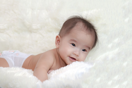 Cute five months asian baby laughing on bright soft carpet.の写真素材