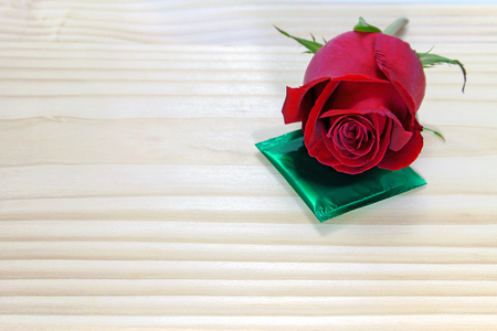 red rose and condom on wooden table, love concept for valentines dayの写真素材