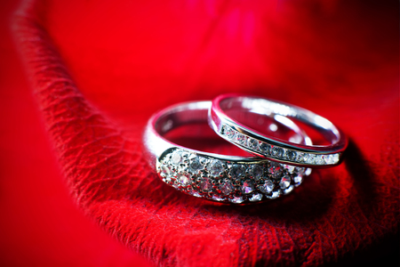 close-up view of two wedding rings on the dark red rose petals, love concept for valentines dayの写真素材
