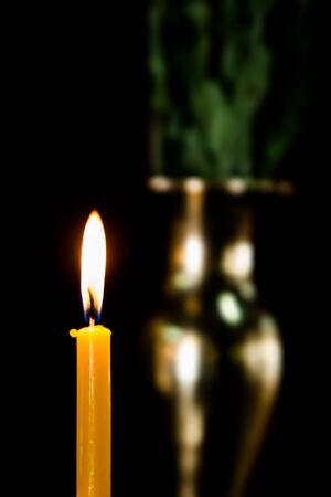 candlelight in the dark, with blurred brass vase backgroundの写真素材