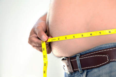 Obese person measuring his belly.の写真素材