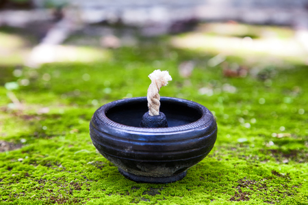 close-up of empty traditional clay lamp on the green moss ground. (shallow depth of field and selective focus)の写真素材