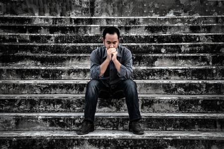 Businessman in frustrated depression sitting on the stairs, in scary abandoned building. The concept of unemployed, sadness, depressed and human problems in dark tone.の写真素材