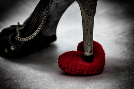 women shoes stomp on broken heart in dark tone., unrequited love., love concept for valentines day.の写真素材