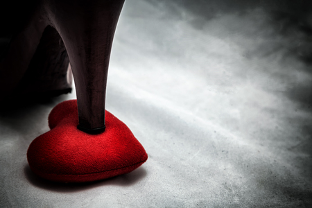 women shoes stomp on broken heart in dark tone., unrequited love., love concept for valentines day.の写真素材