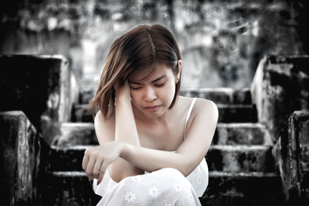 woman in frustrated depressed sitting on stairs, crying and contemplating suicide, in scary abandoned building, Concept of unemployed, sadness, depression, broken heart and human problem in dark tone.の写真素材