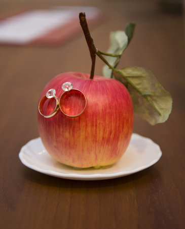 Wedding rings hanging on a red Apple. Wedding. Ceremony.の写真素材