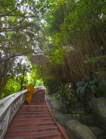 Unknown monk walks up the steps in one of the temples of Thailand.の写真素材