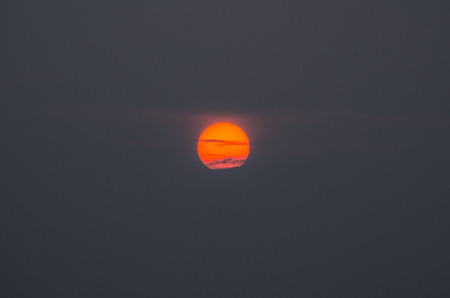 Lonely red sun on a grey empty sky. The sunset in Japan.