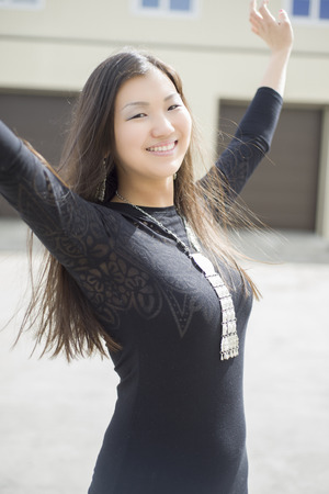 Beautiful Chinese the girl in the yard of his house dancing. In the background a house and a garage.の写真素材