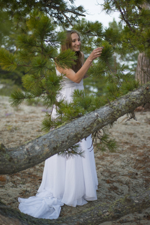 Beautiful young girl in a white dress, walking in the woods on the seashore.の写真素材