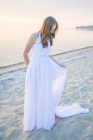 Beautiful girl walking on the beach in front of the stunning sunset.の写真素材