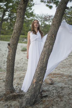 Beautiful young girl in a white dress, walking in the woods on the seashore.の写真素材
