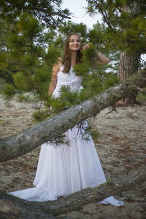 Beautiful young girl in a white dress, walking in the woods on the seashore.の写真素材