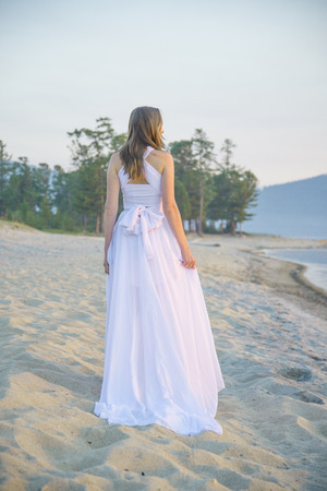 Beautiful girl walking on the beach in front of the stunning sunset.の写真素材