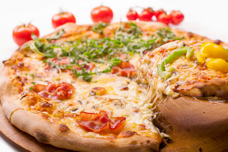 Freshly baked Pizza with one slice lifted up from the plateの写真素材