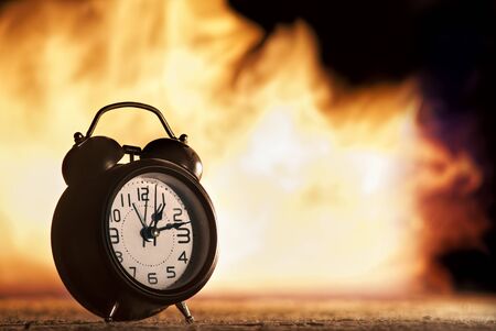 Dramatic picture of alarm clock with fire in the backgroundの写真素材