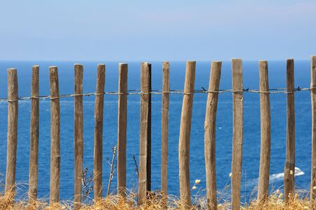 Wooden fence in front of a blue seaの写真素材