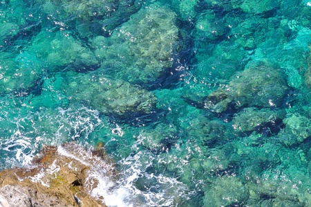 Transparent sea slamming on rocksの写真素材